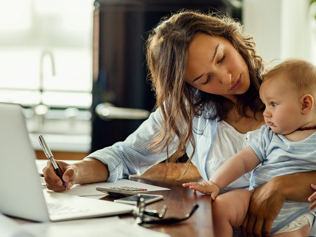 woman holding baby and using laptop on Bestow life insurance website