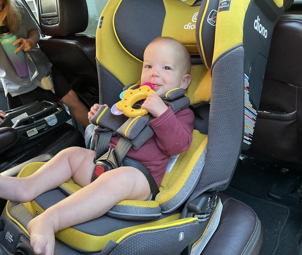 baby boy sitting in seat smiling while holding toy