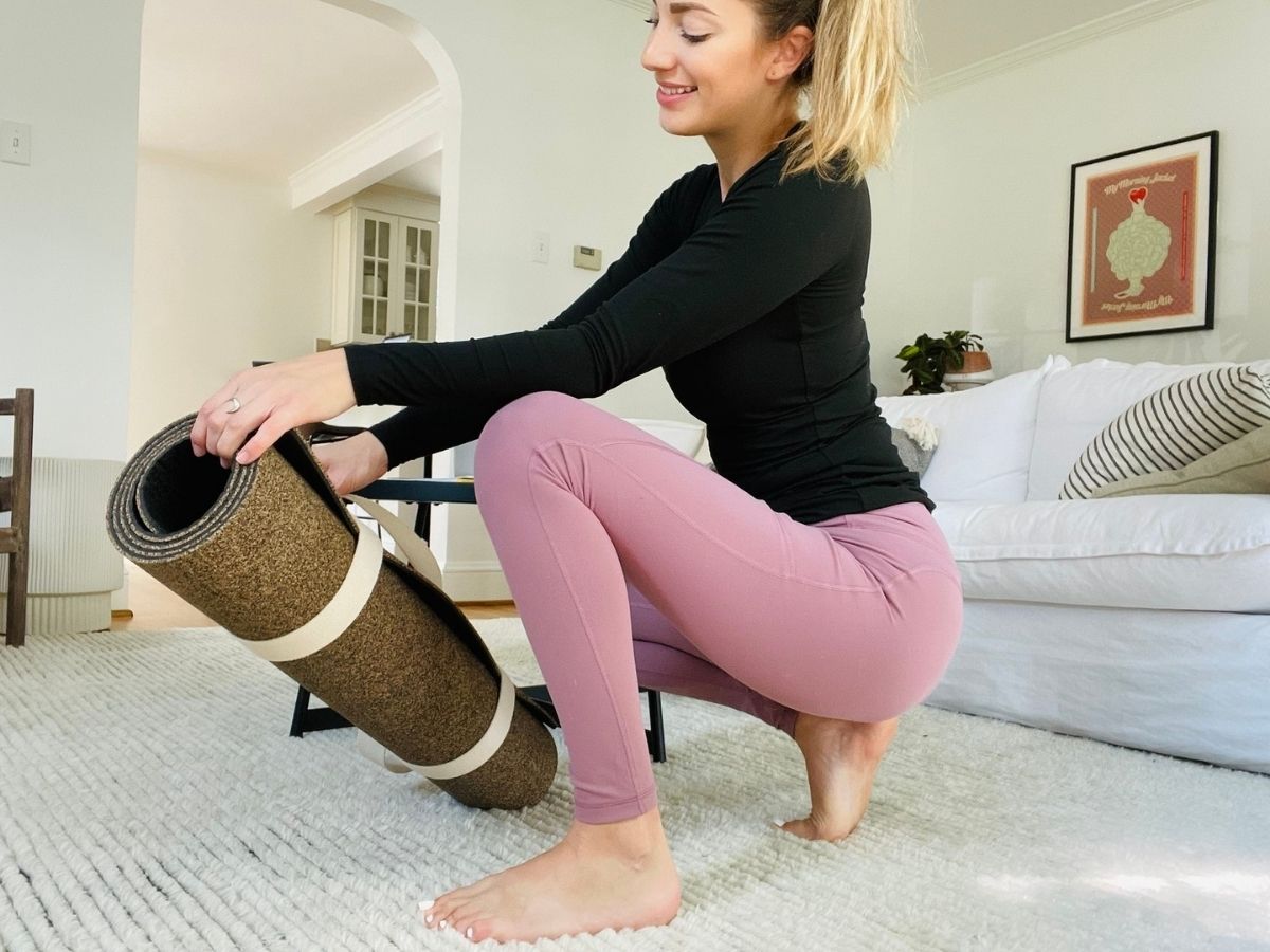 woman squatting down taking out yoga mat