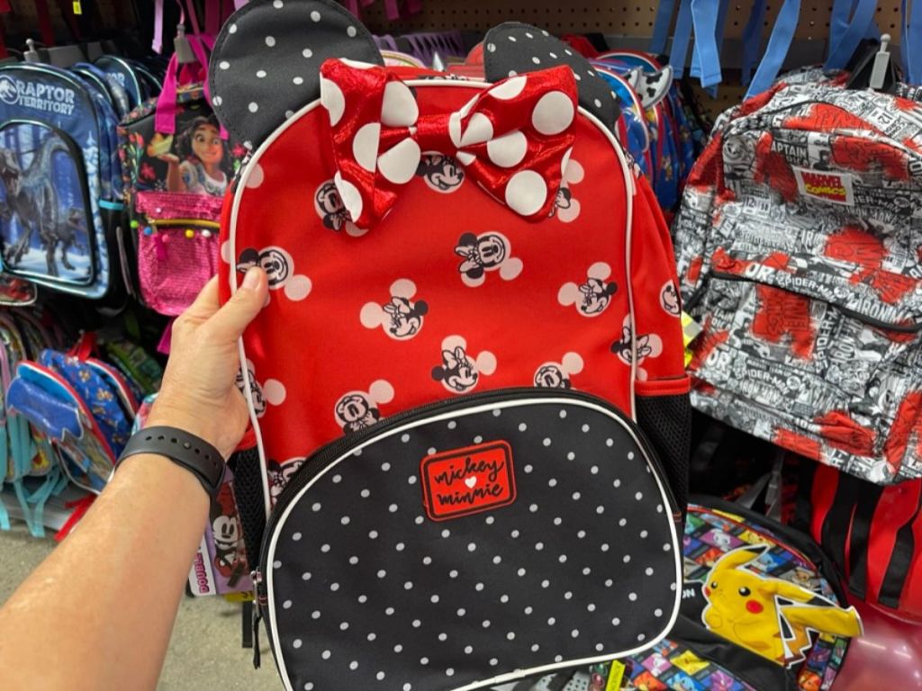 a woman's hand holding a minnie mouse backpack