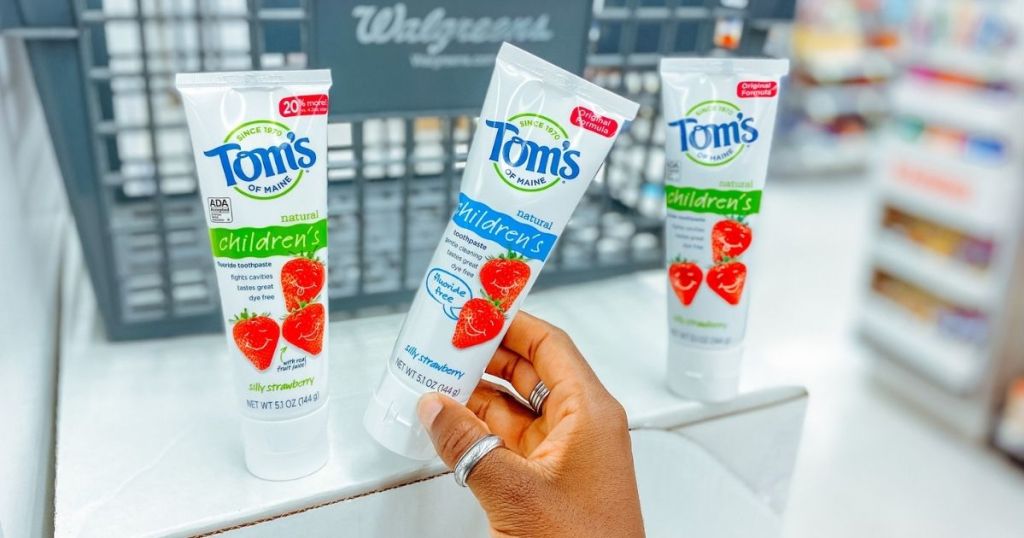 hand pulling white tube of children's toothpaste off shelf 