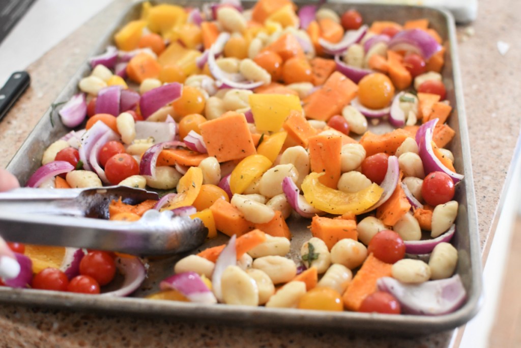 tossing ingredients for sheet pan gnocchi in olive oil