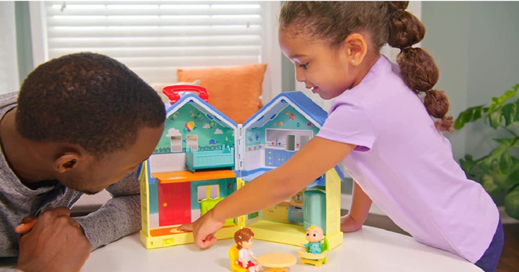 girl and man in front of toy house 