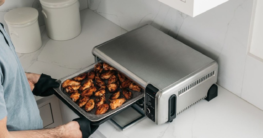 hands putting food in air fryer 