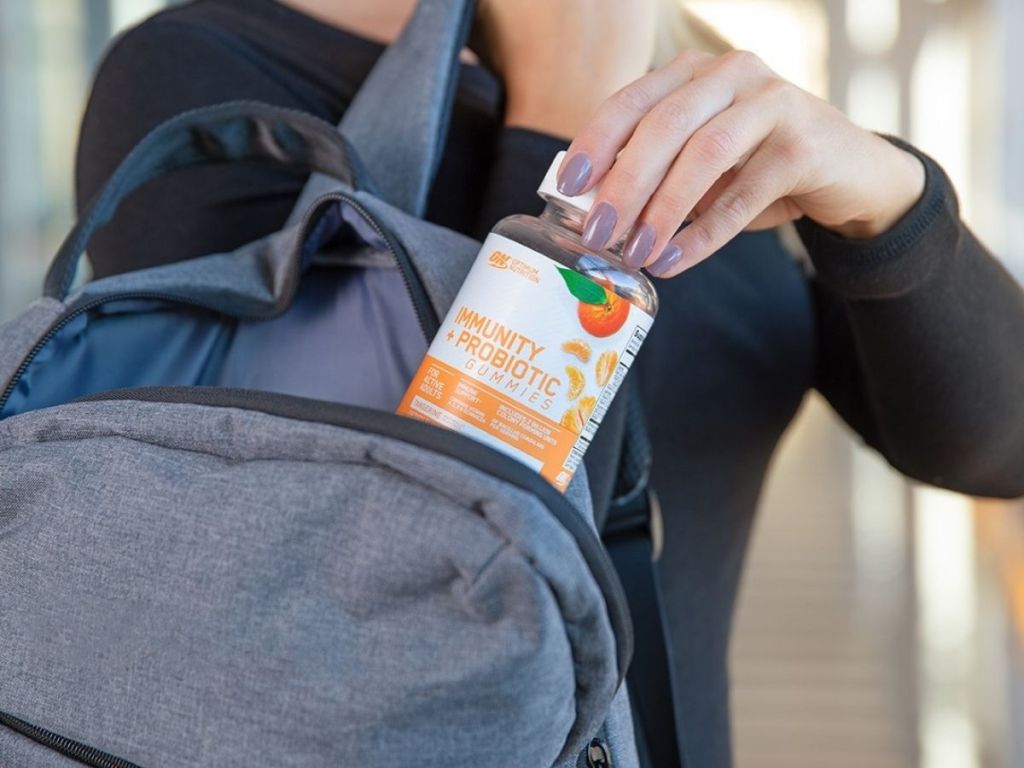 woman putting immunity + probiotic gummies in backpack