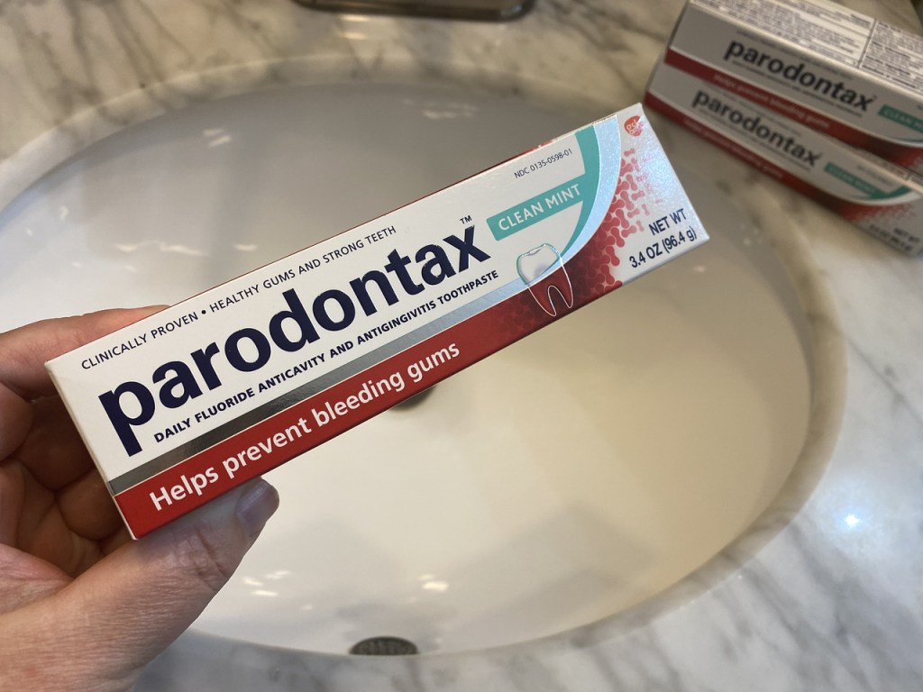 hand holding Parodontax Toothpaste over sink