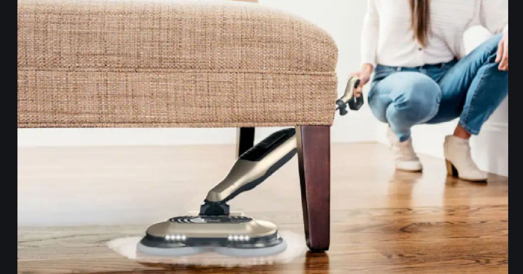 woman using steam mop under chair 