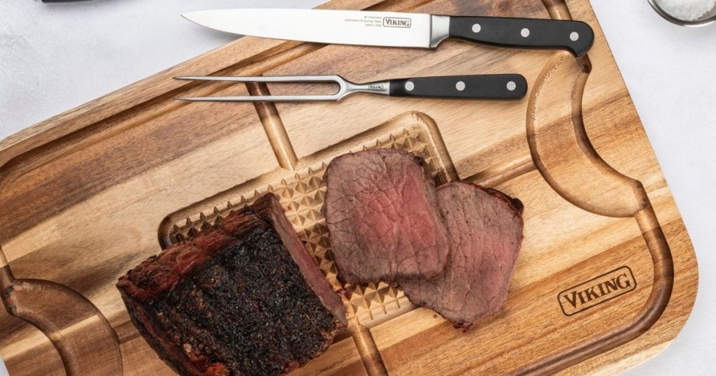 cutting board with meat and knives on it