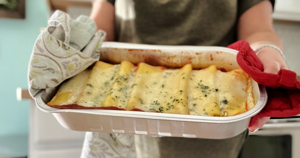 holding a pan of manicotti