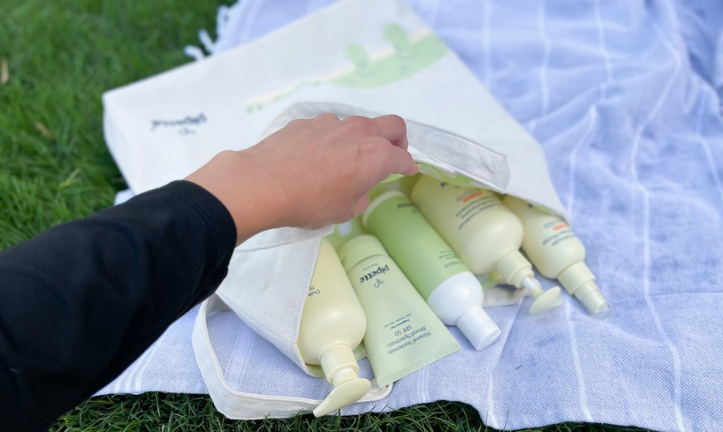 hand holding open tote bag with pipette baby products