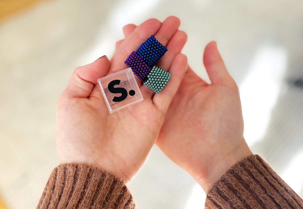 hand holding various colors of speks magnetic balls with clear case