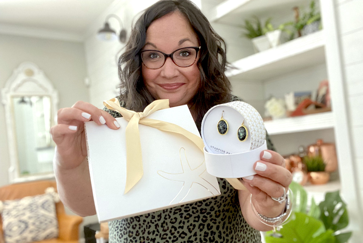 woman holding starfish project jewelry gift boxes with earrings