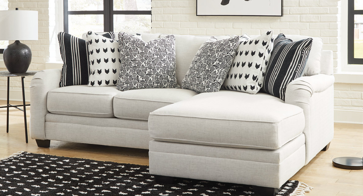 Ashleys furniture with throw pillows displayed on it and a rug