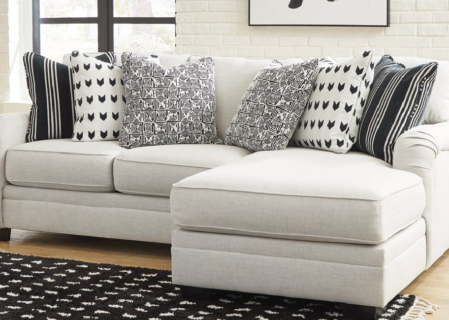 Ashleys furniture with throw pillows displayed on it and a rug