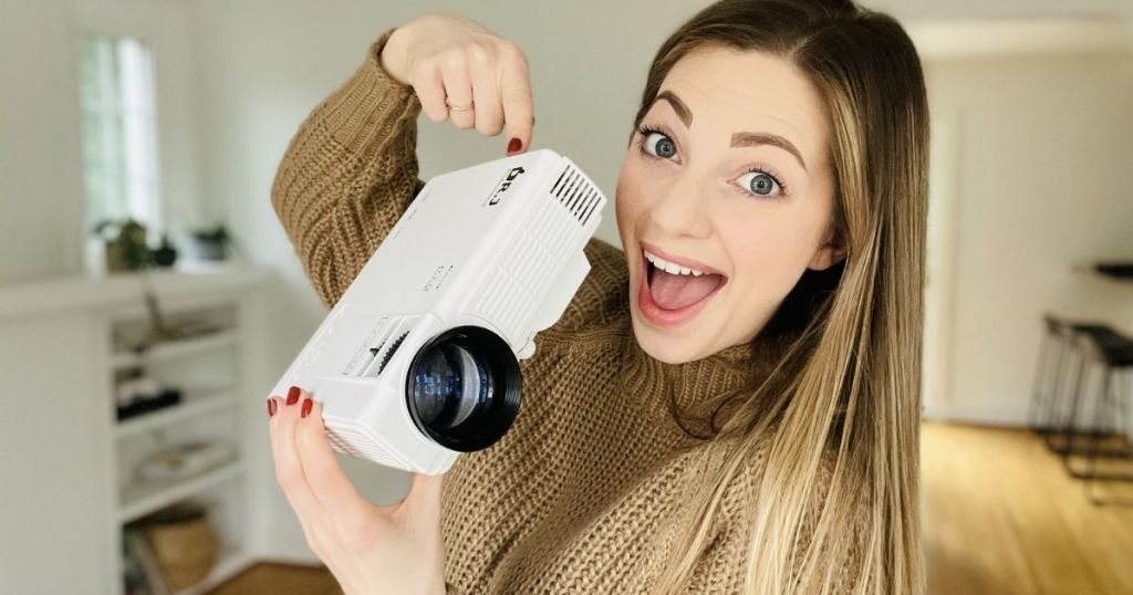 woman holding a mini projector and pointing at it