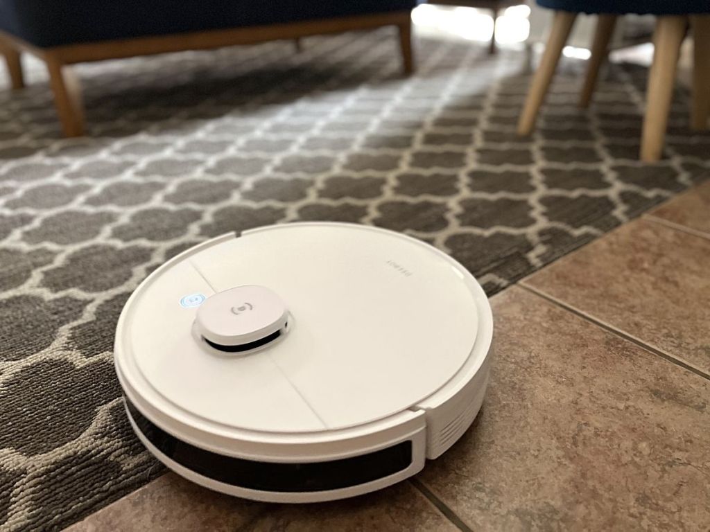 white robot vacuum half on carpet half on floor