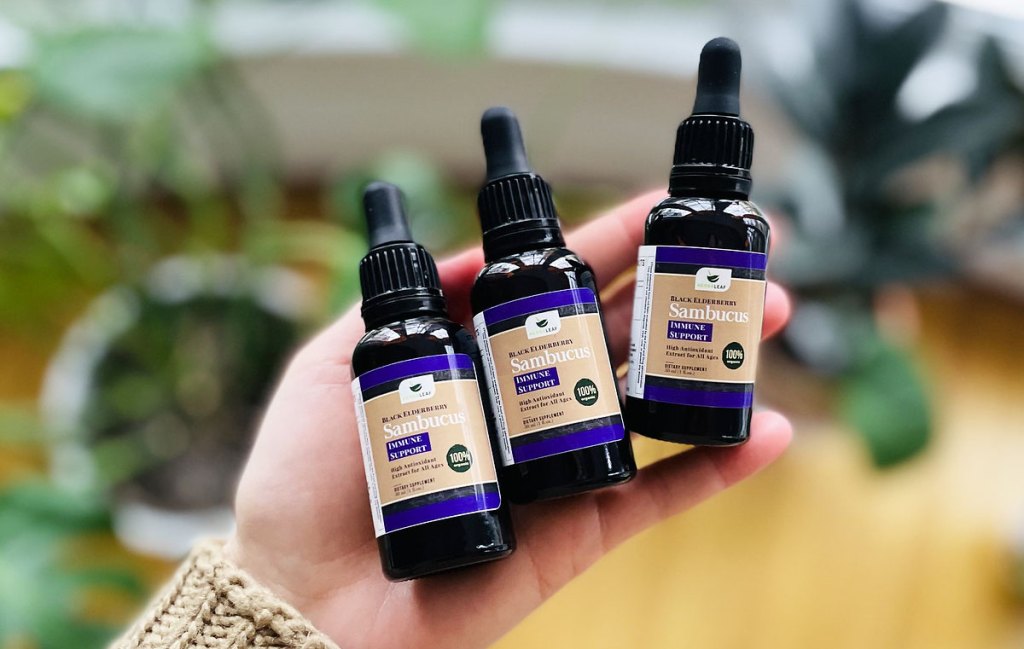 holding 3 bottles of elderberry extract