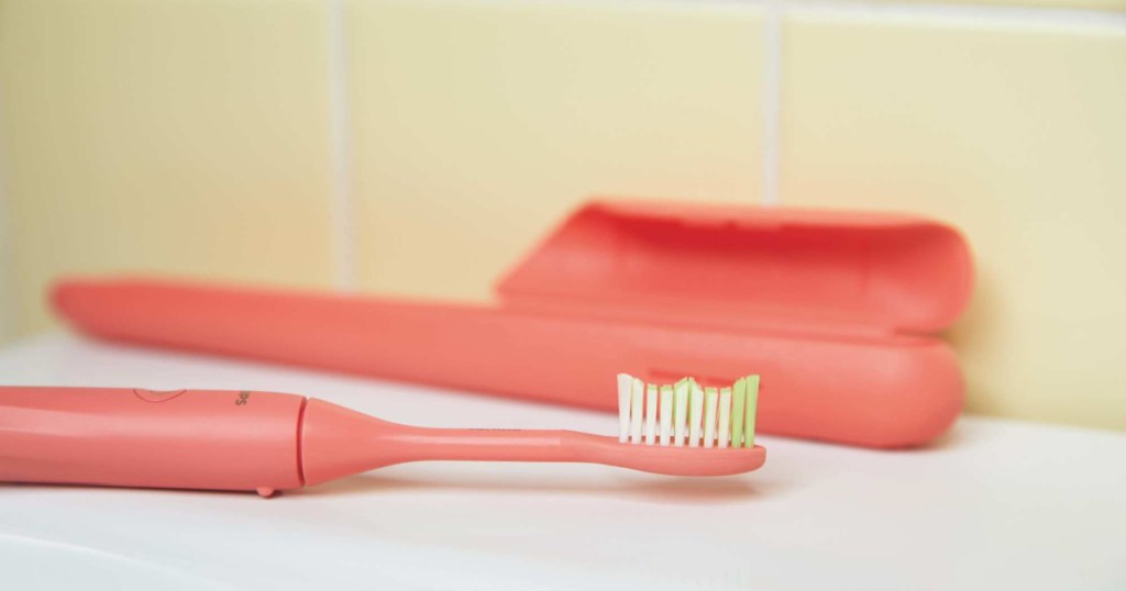 coral battery toothbrush on counter