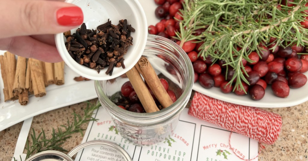 adding cloves to jar of potpourri