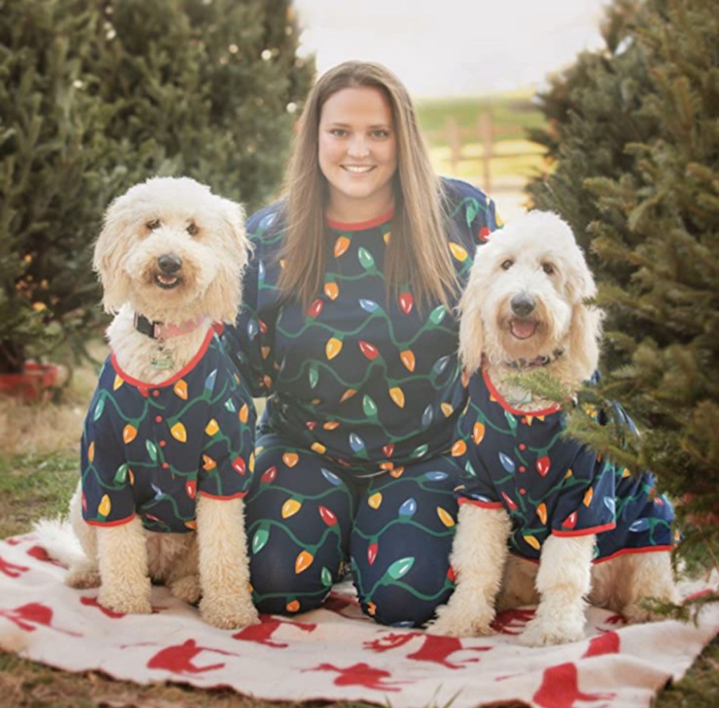 woman sitting on blanket next to two dogs wearing the best matching family pajamas