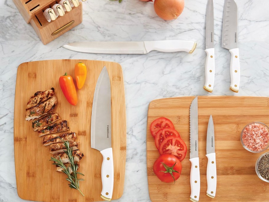 white farberware knife laying on cutting boards with veggies 