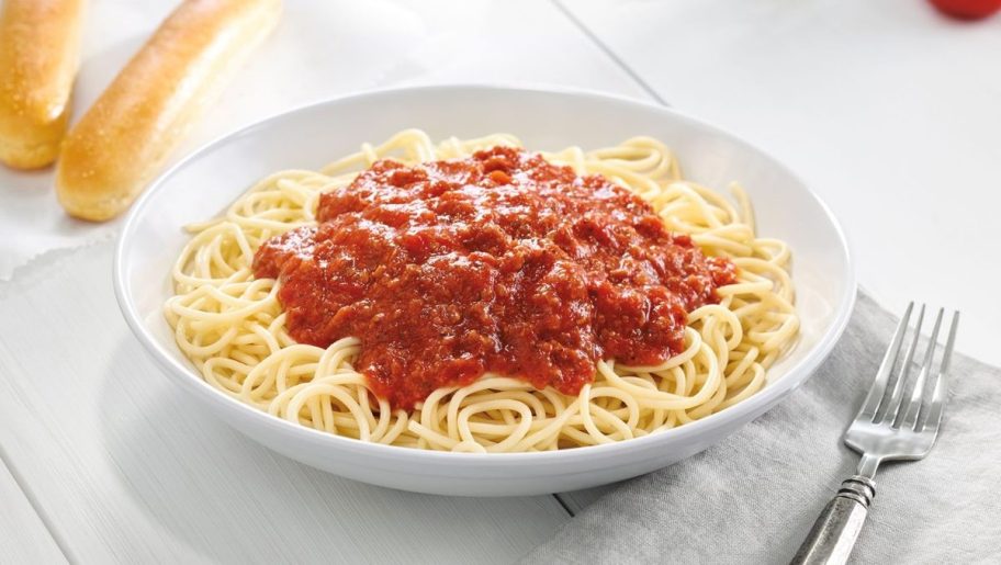 bowl of spaghetti with breadsticks