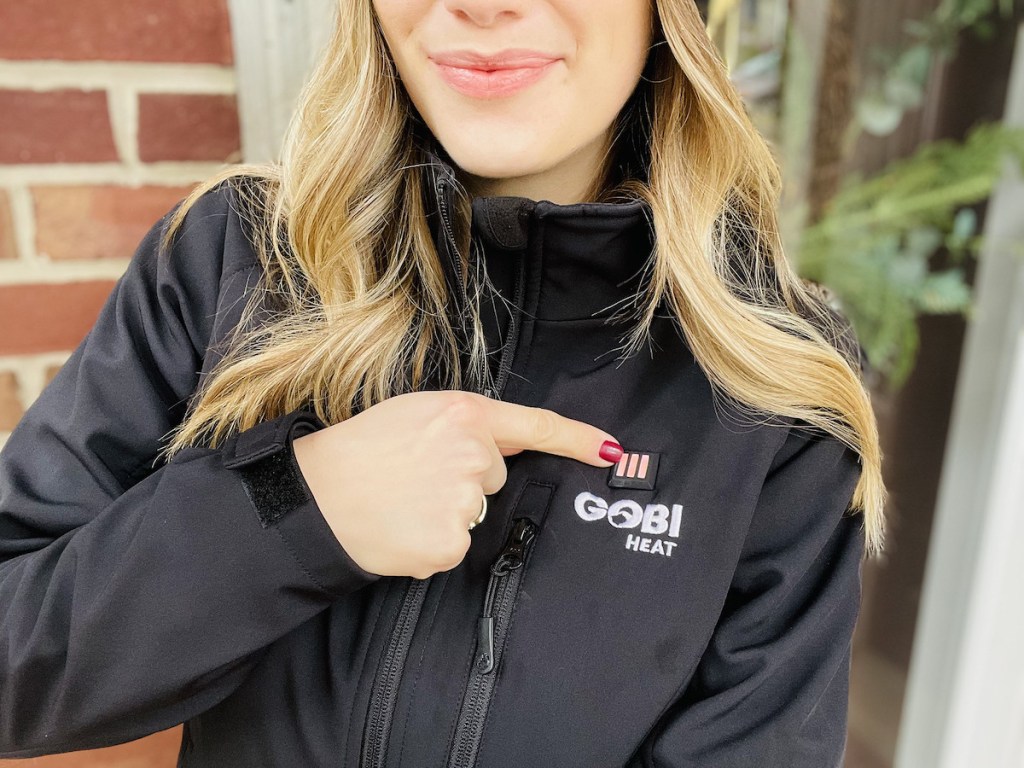 woman pointing finger to button on black jacket