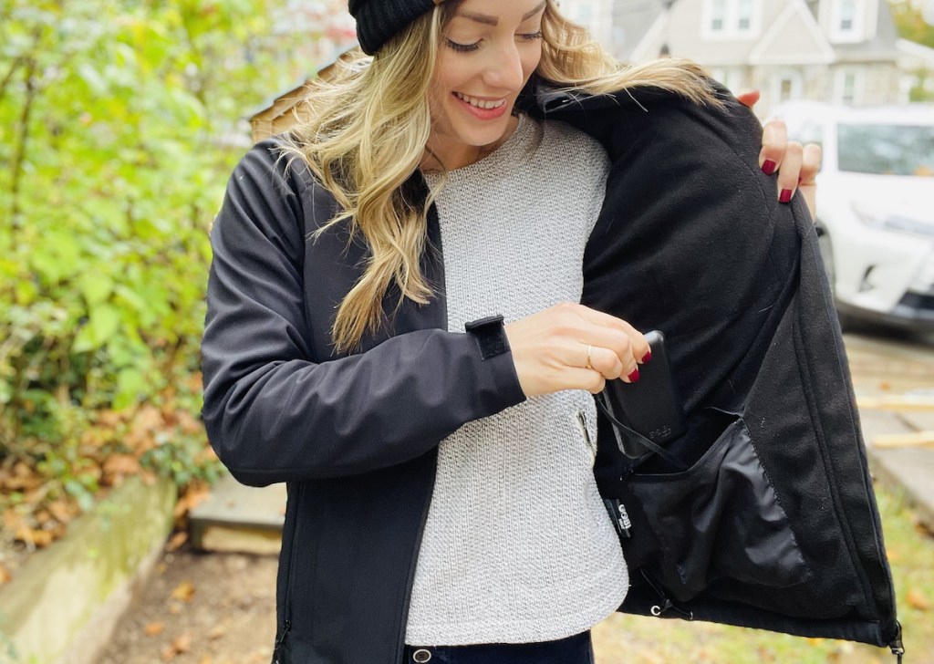 woman holding battery pack putting it in zipper pocket of coat