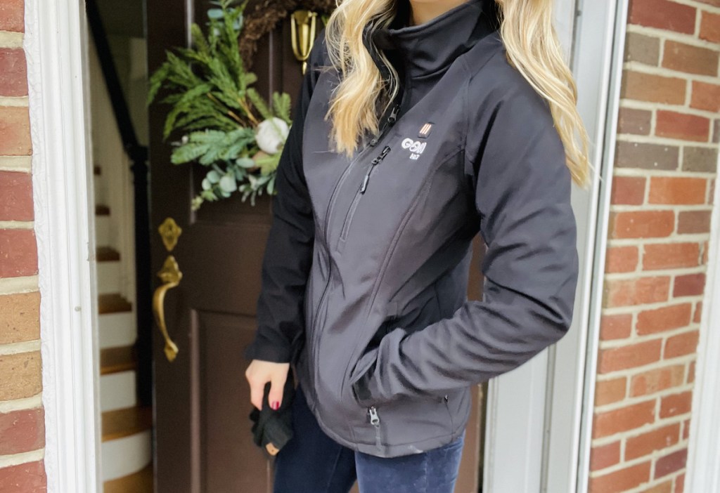 woman standing in open front doorway wearing black coat