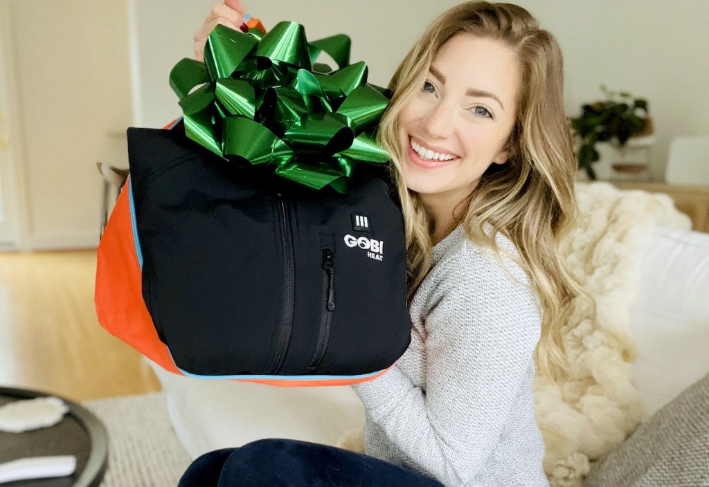 woman holding black coat with large green bow on top