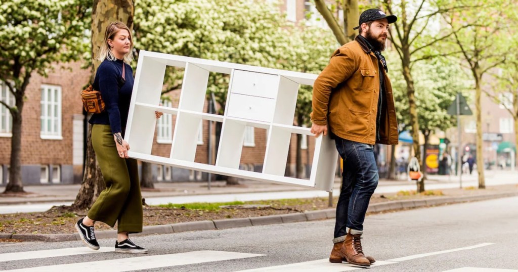 two people carrying furniture across the street