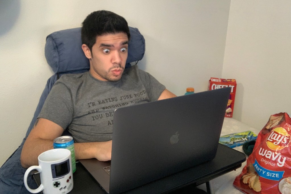 man sitting in chair looking surprised at laptop