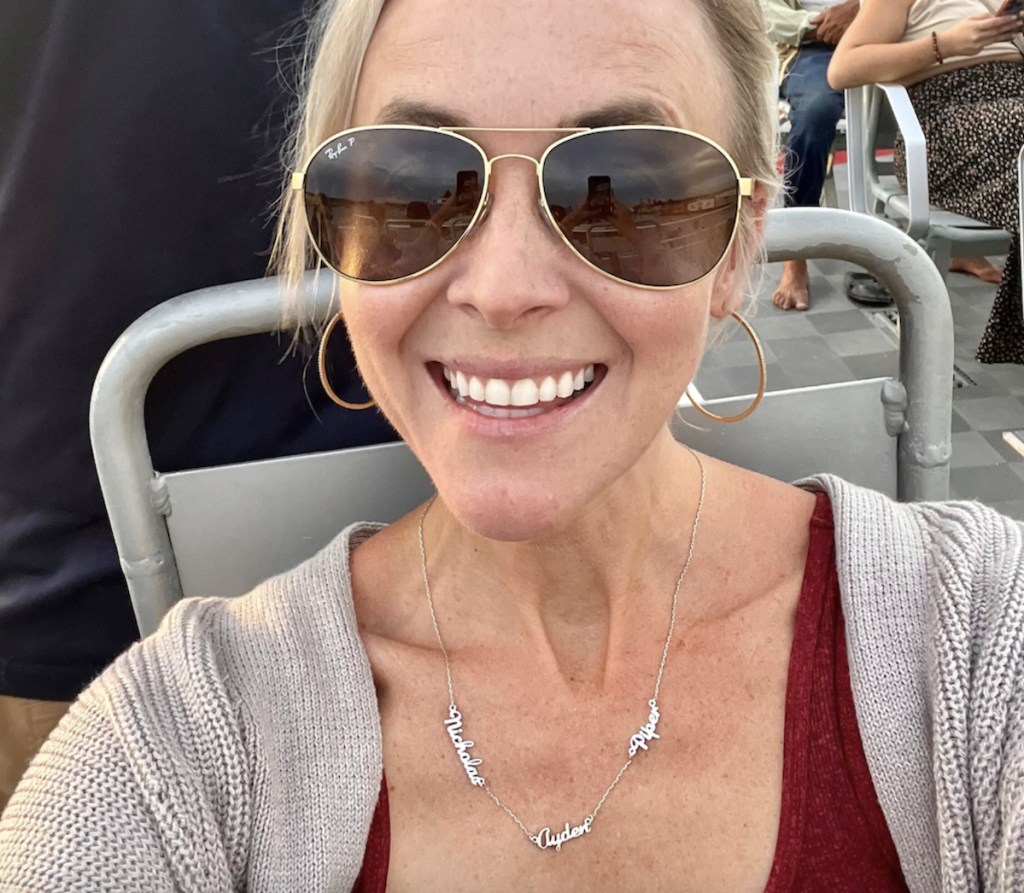 woman wearing name necklace and ray ban sunglasses