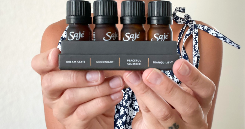 holding 4 bottles of Saje essential oils 