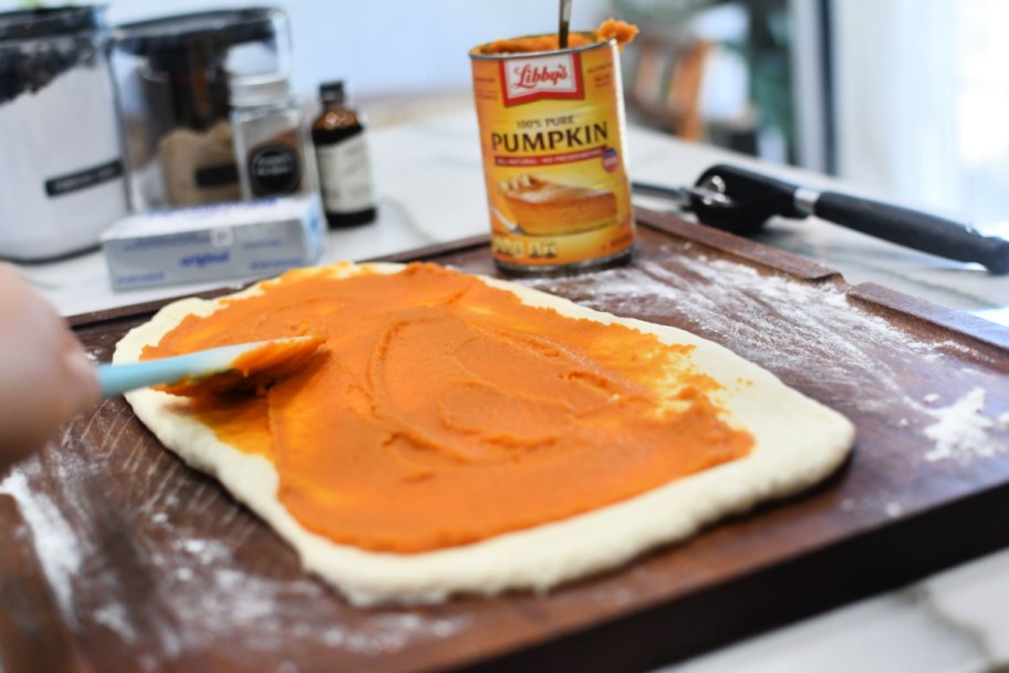 spreading pumpkin puree on bread dough