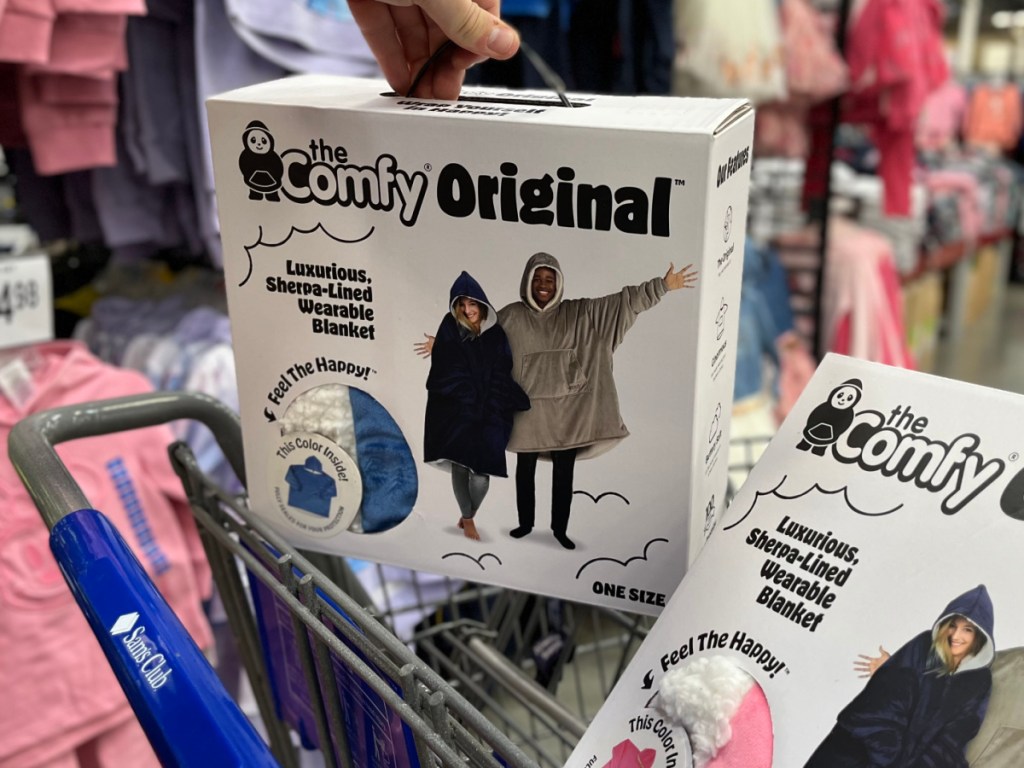 hand by grocery cart holding box with blanket in store