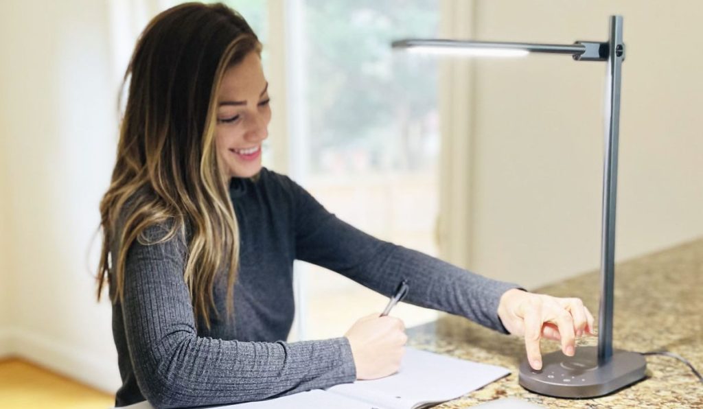 woman adjusting desk lamp