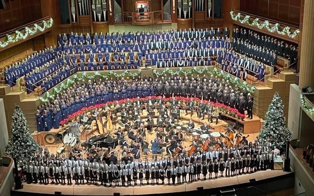 tons of choir and orchestra people performing on stage 