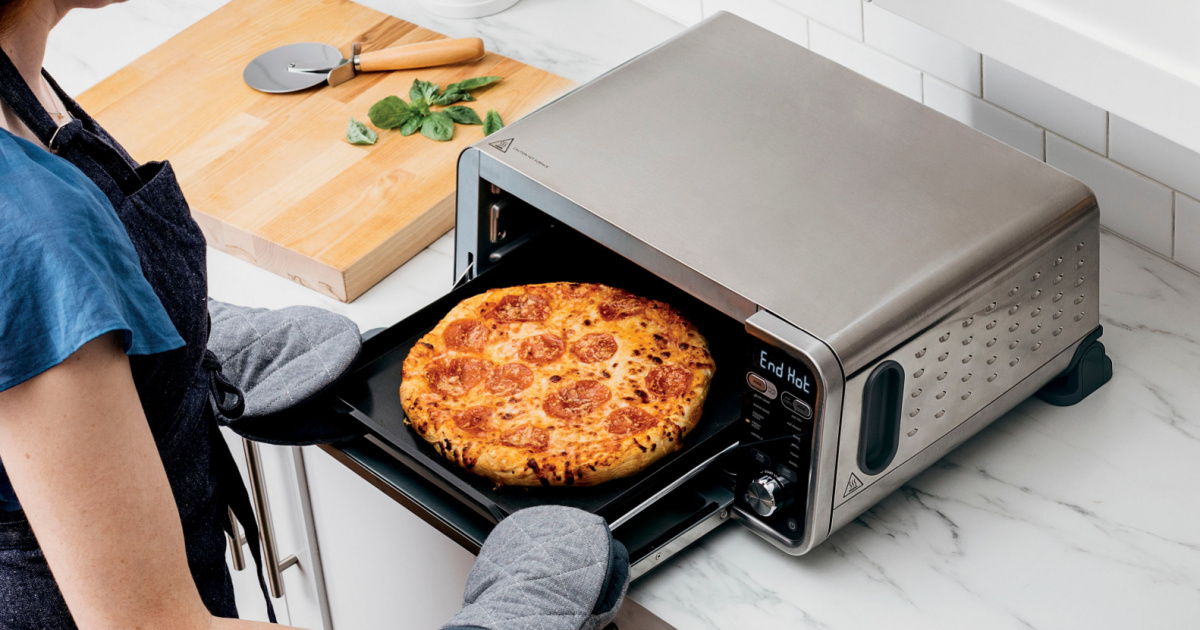 woman putting a pizza in a Ninja Foodi Flip 11-in-1 Convection Toaster Oven