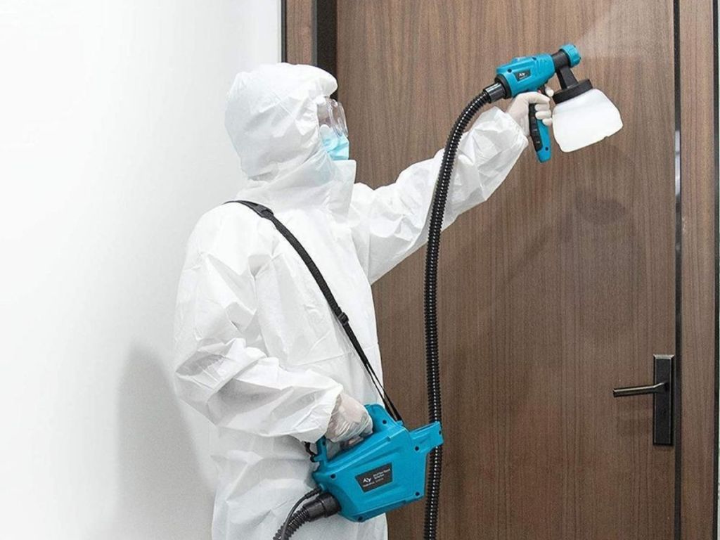 person using paint gun to paint door