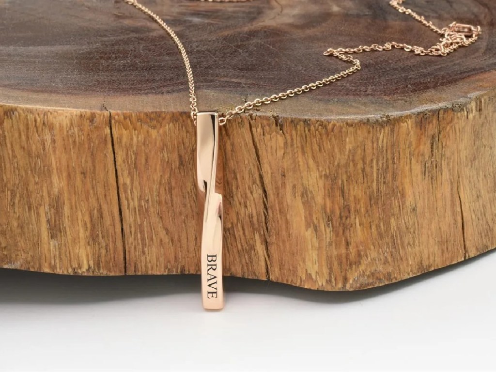 rose gold bar necklace laying on wood stump