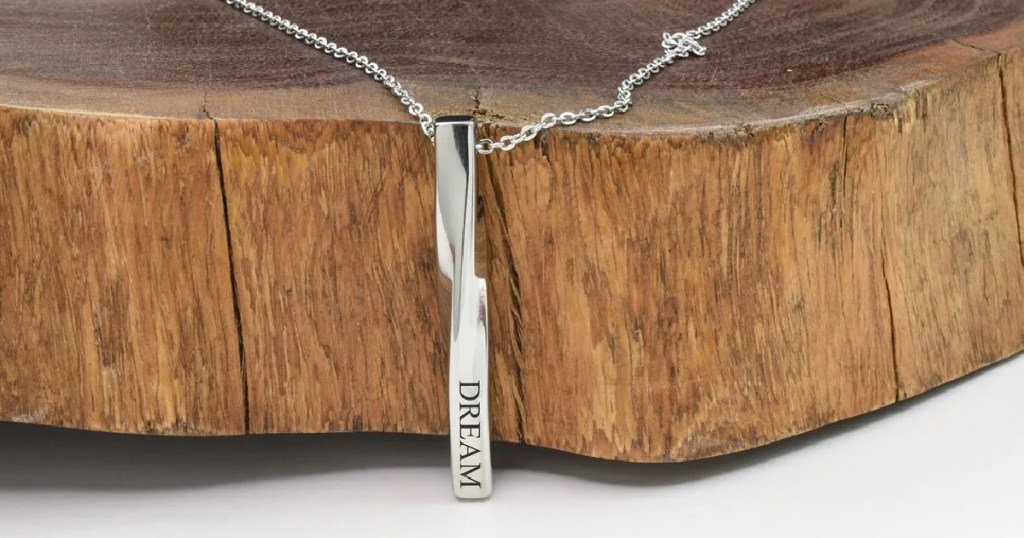 silver bar necklace laying on wood stump