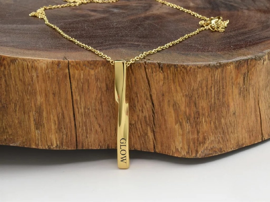 gold bar necklace laying on wood stump