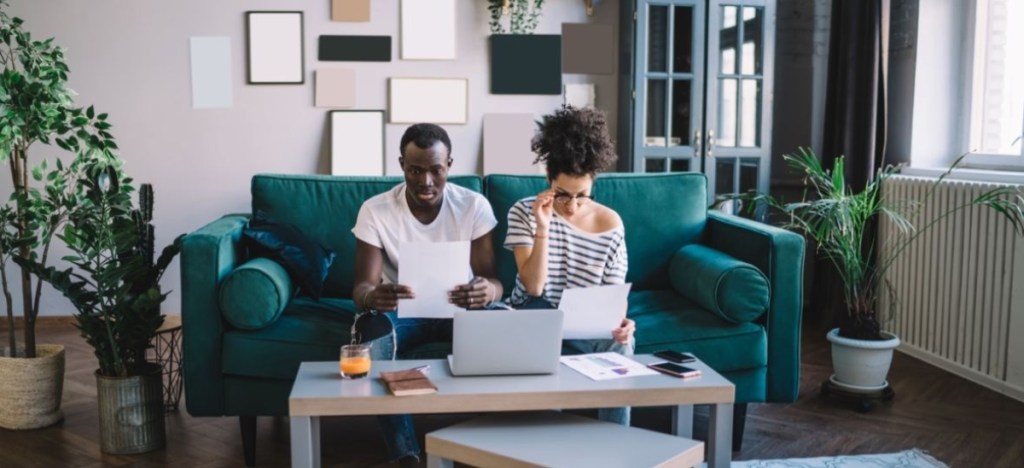 couple on couch with laptop and papers