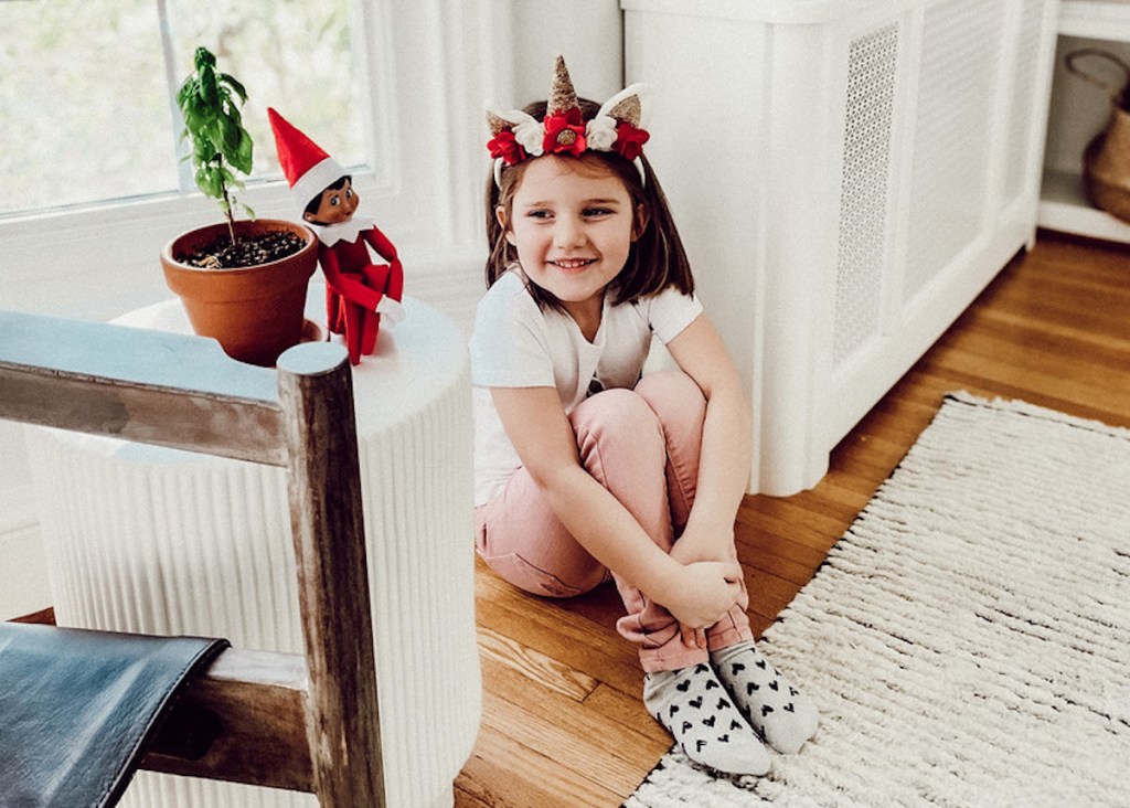 girl sitting with Elf on the shelf on floor