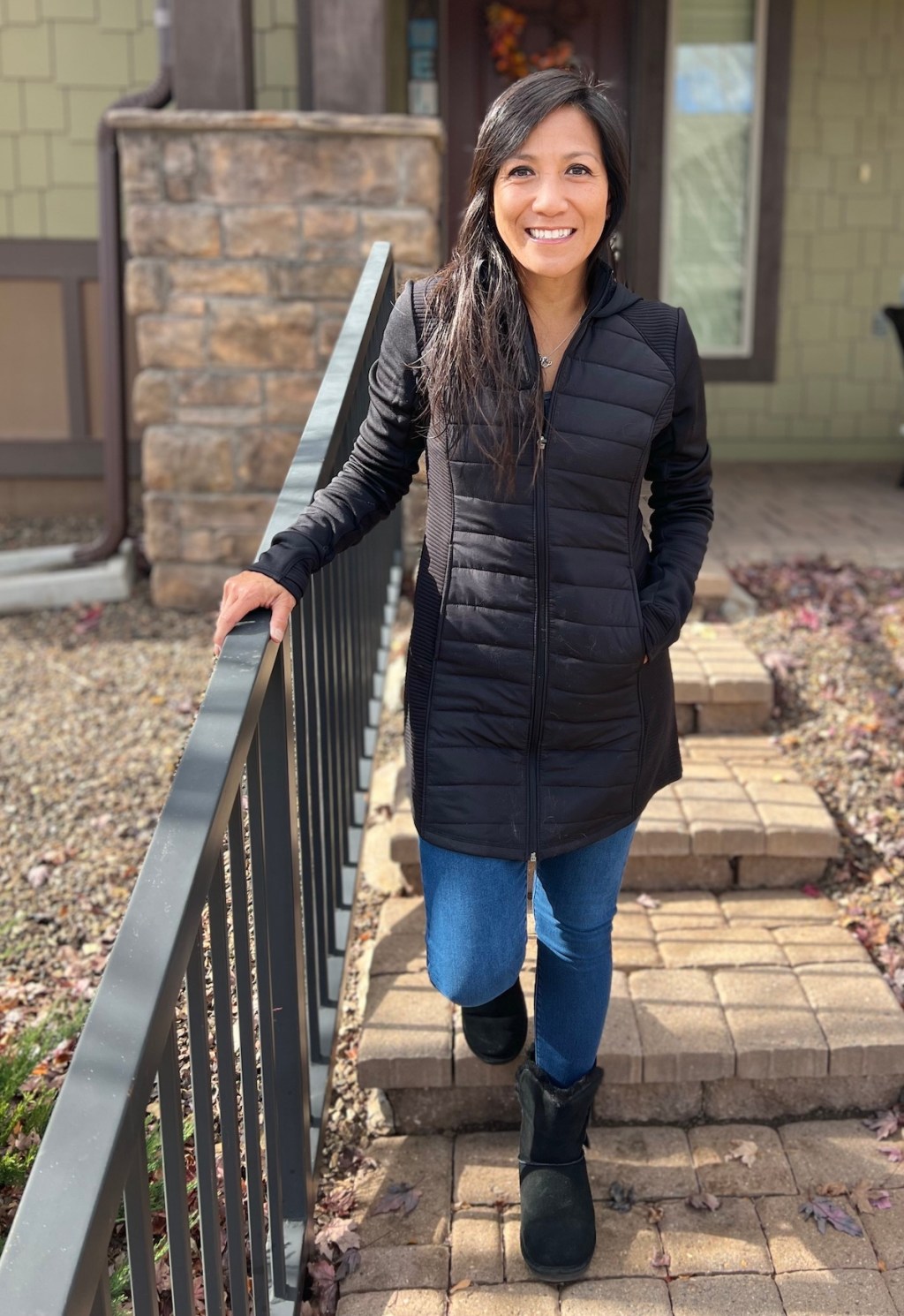 woman standing on steps outside smiling wearing black parka jacket