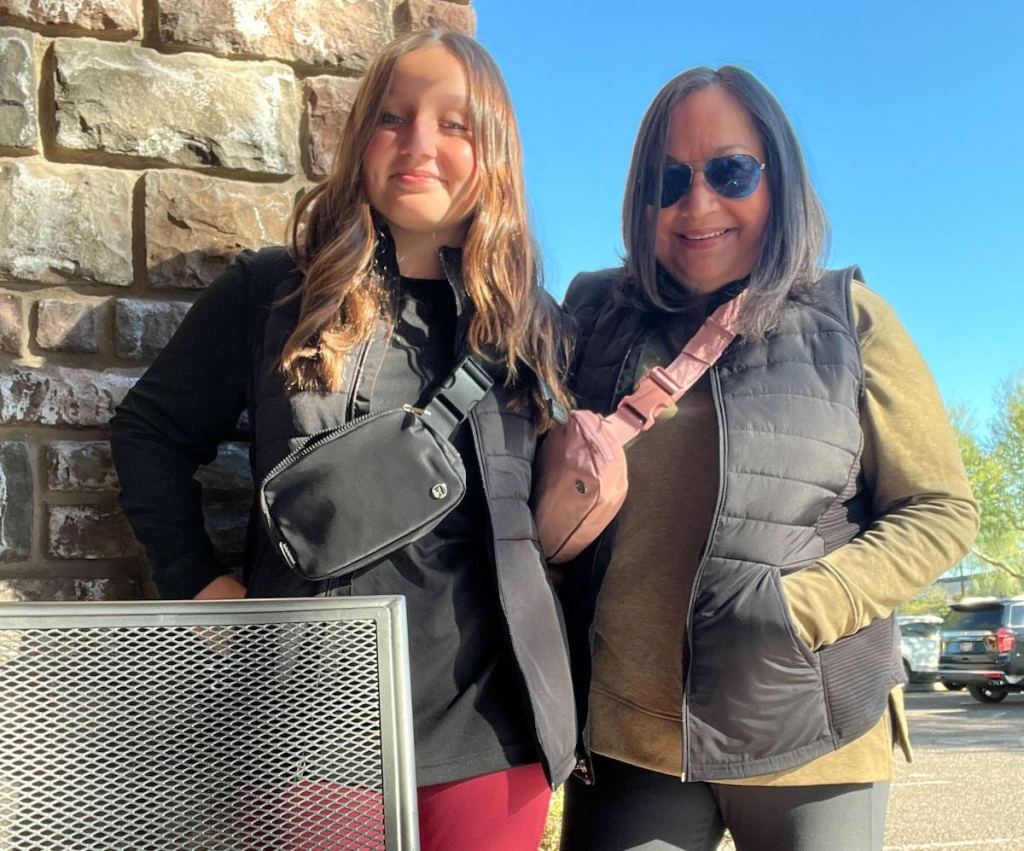 two women wearing black kohls vests with lululemon belt bags