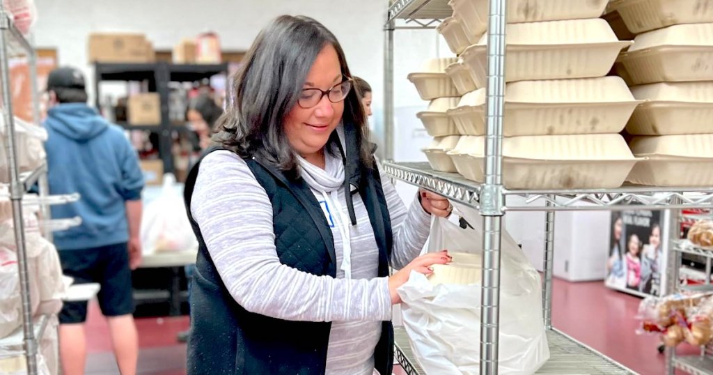 woman packing meals in to go boxes on food pantry shelf