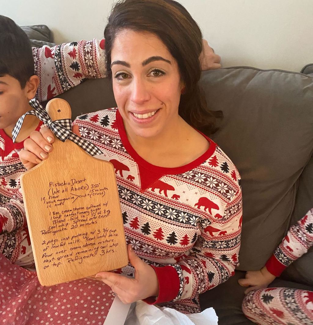 woman holding a cutting board with handwriting engraved on front