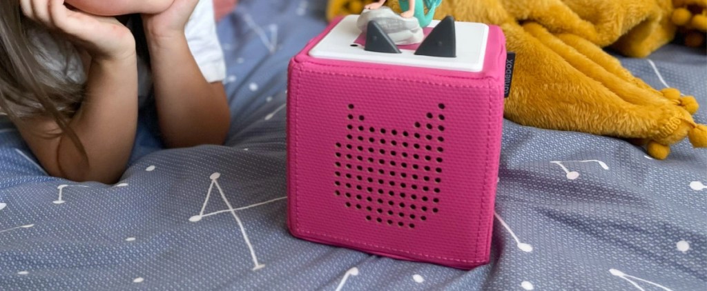 young girl looking at a pink toniebox